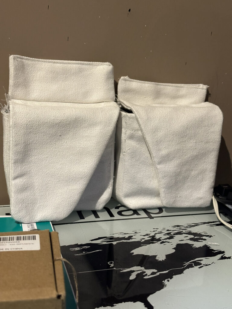 Two white fabric costume pouches on a worktable
