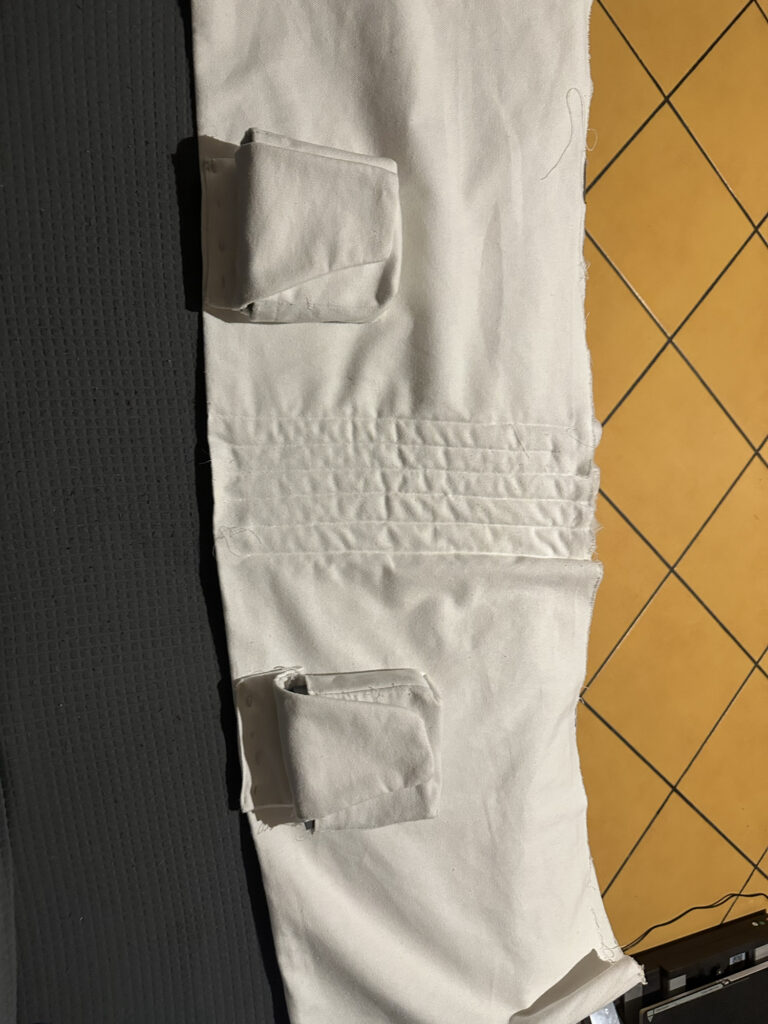 White fabric costume piece with sewn pocket and textured panel