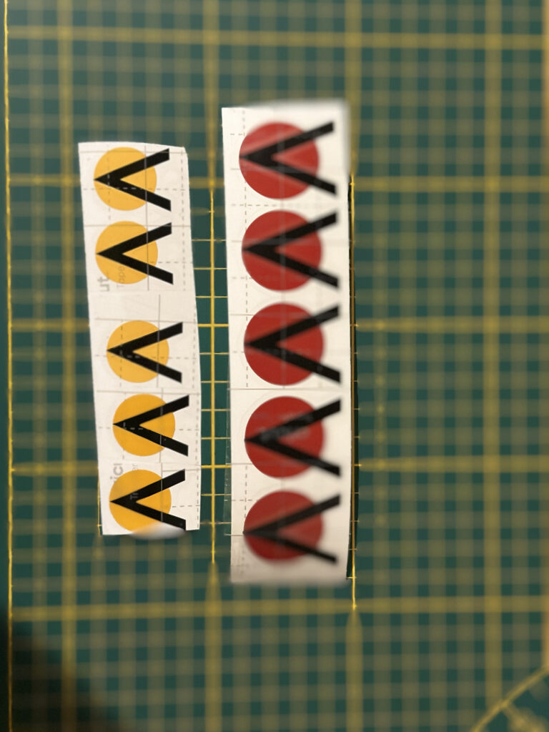Rows of yellow and red graphic decals on a cutting mat