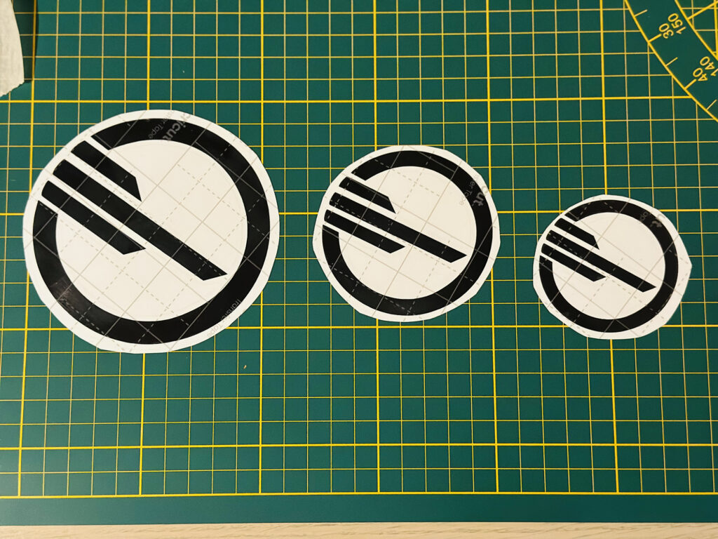 Black circular emblem stickers on a cutting mat