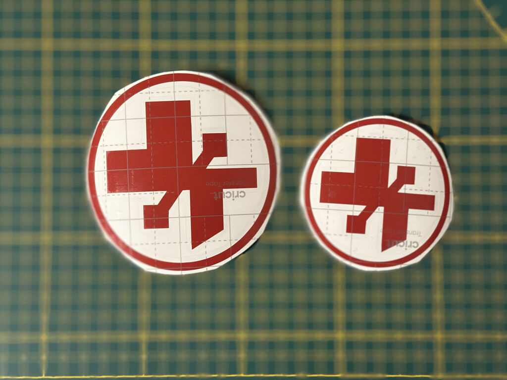 Two red circular decals on a green cutting mat