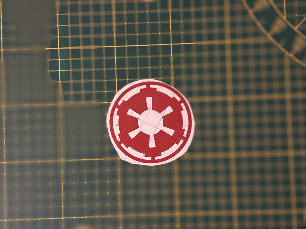 Red circular emblem sticker displayed on a grid surface