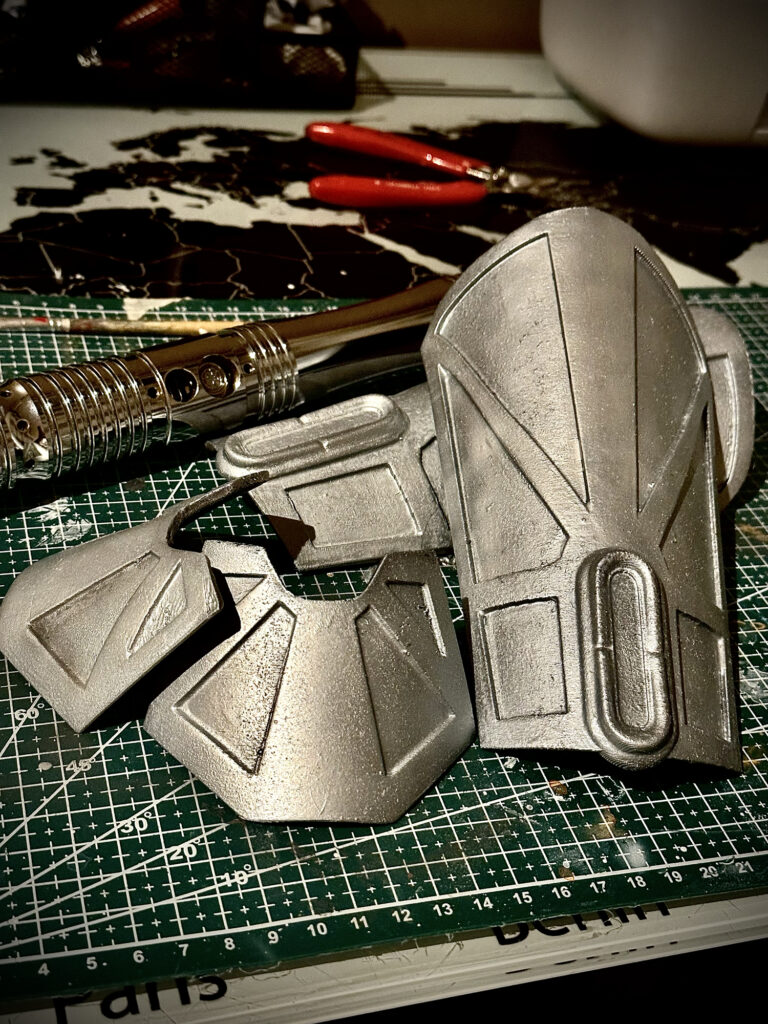 Silver costume armor pieces laid out on a cutting mat